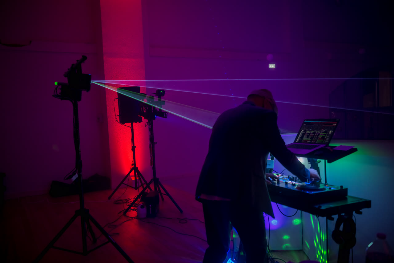 DJ Magic OZ de dos à sa console – laser rouge, ambiance soirée
